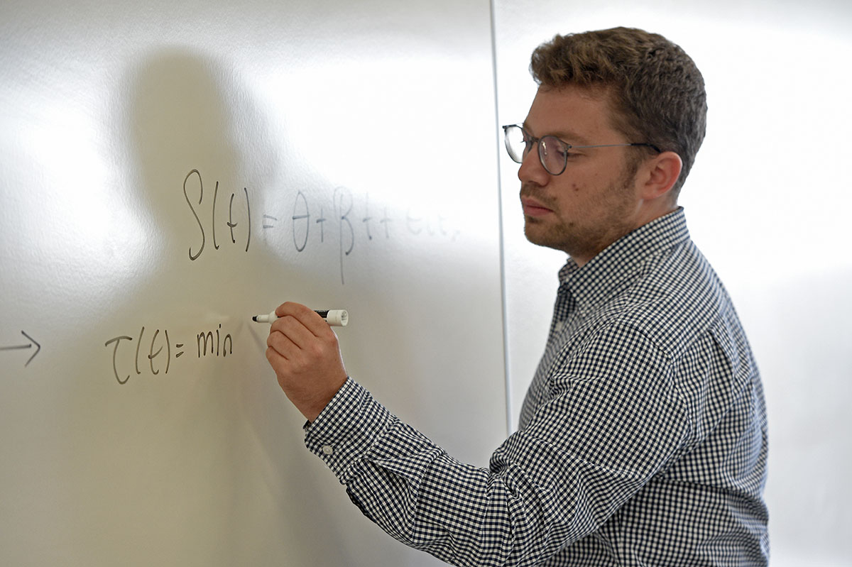 Murat Yildirim writing equations on a whiteboard